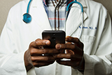 Doctor holding smartphone conducting telemedicine.