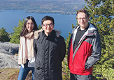 Three hikers on a mountain, with a view of Lake George in the background