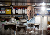RNA Institute Director Andy Berglund smiles behind his lab's equipment