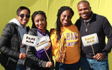 A mom and dad and two college young women in the middle, root for the Great Danes and hold up signs saying so.