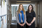 Student Margeaux Cannon and Professor Lisa McAndrew smile in a School of Education hallway