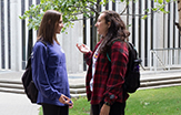 Two female students talk outside one of the quad residence halls on campus.