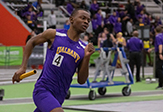 A Ualbany relay runner holds a gold baton and rounds the final turn