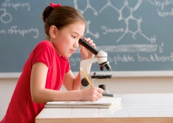 A student at a microscope in a classroom