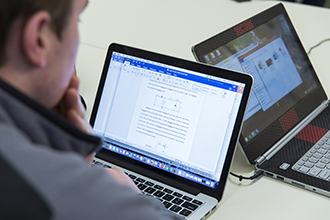 Student works on a laptop while seated at a desk.