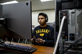UAlbany eSports player with headset on in the team's arena at Draper Hall.