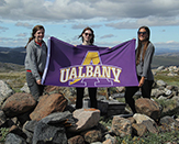 Students take photo in Greenland holding a UAlbany flag.