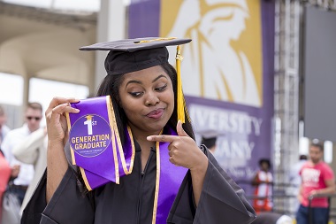 UAlbany graduate proudly points to her first-generation badge at commencement.