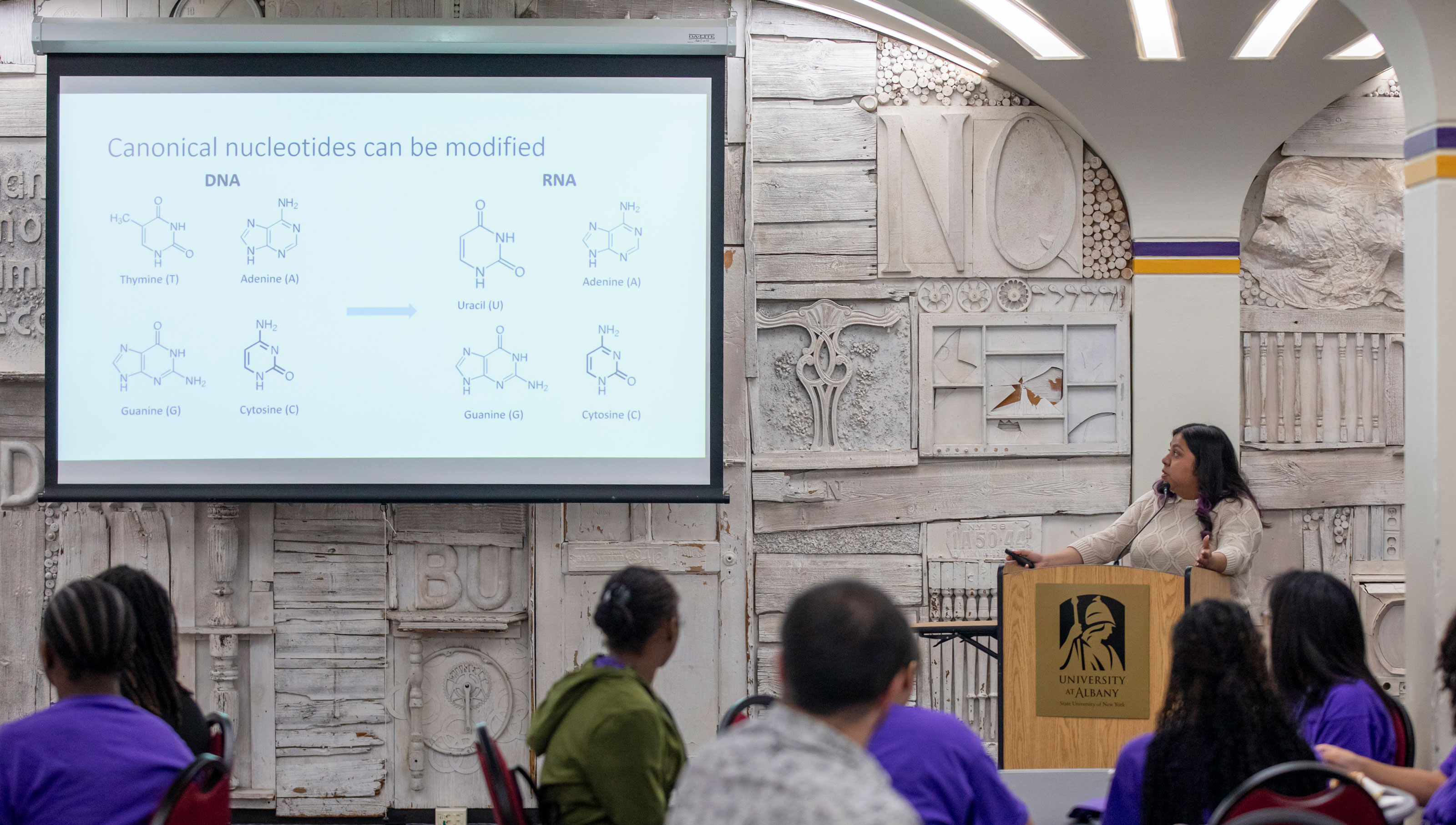 Health disparities doctoral fellow Esperanza Rosas presents a slide titled, "Canonical nucleotides can be modified," with images of RNA and DNA compounds.