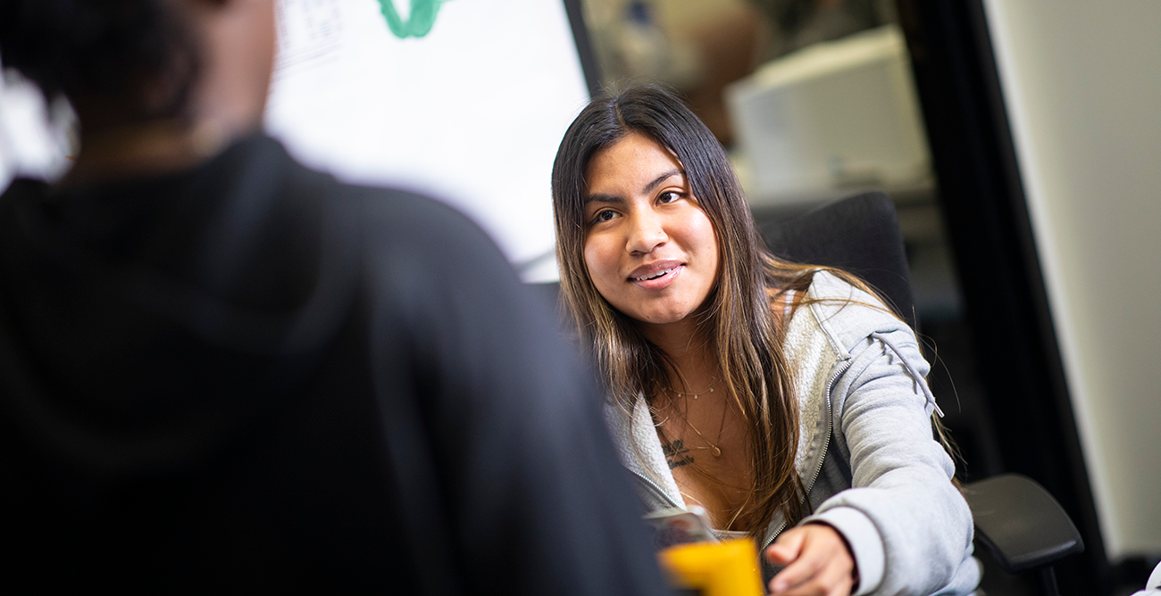 A student greets another student at the front desk of the Writing Center.