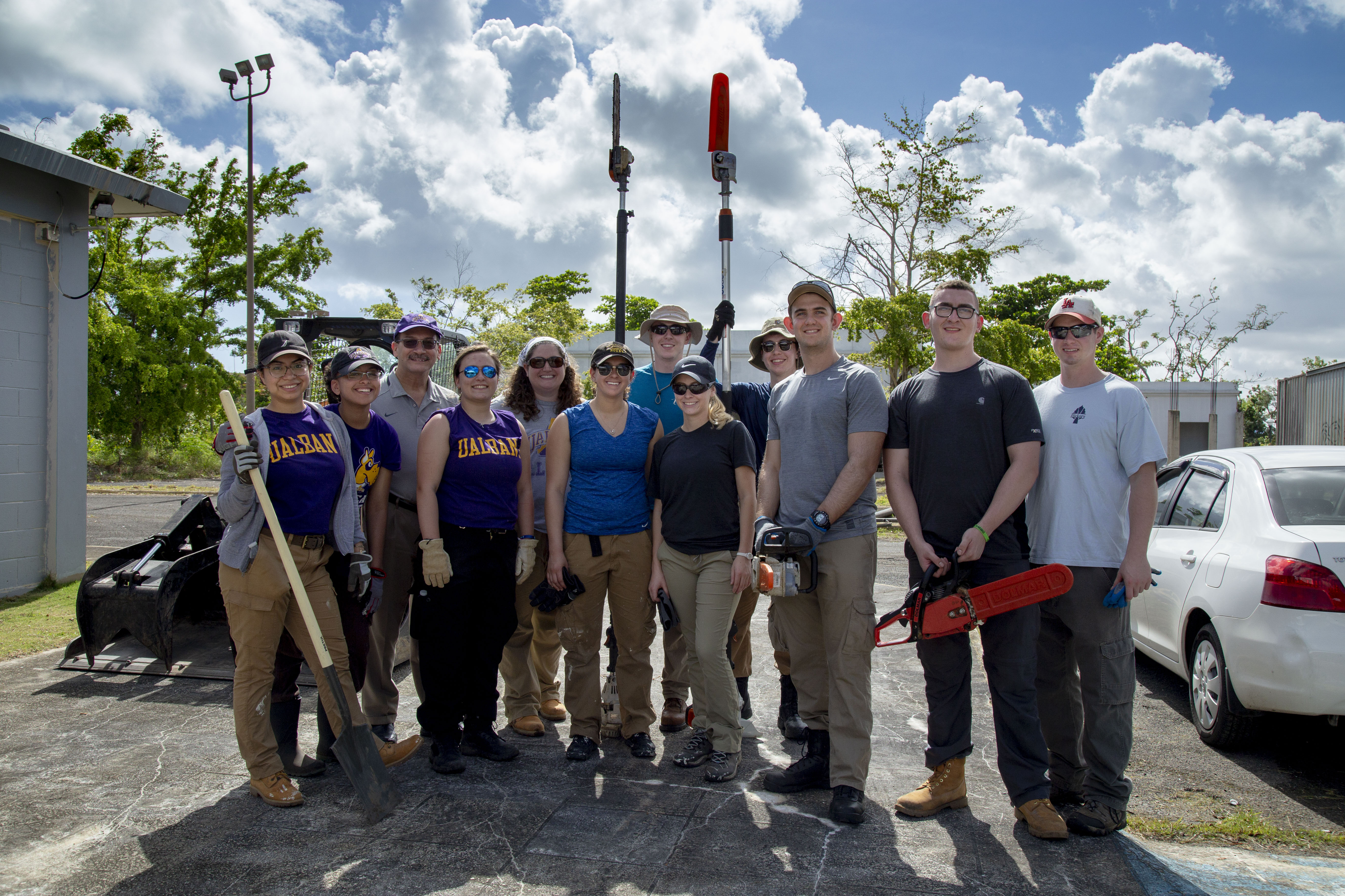 UAlbany volunteers stand together amidst debris in Puerto Rico following Hurricane Maria.