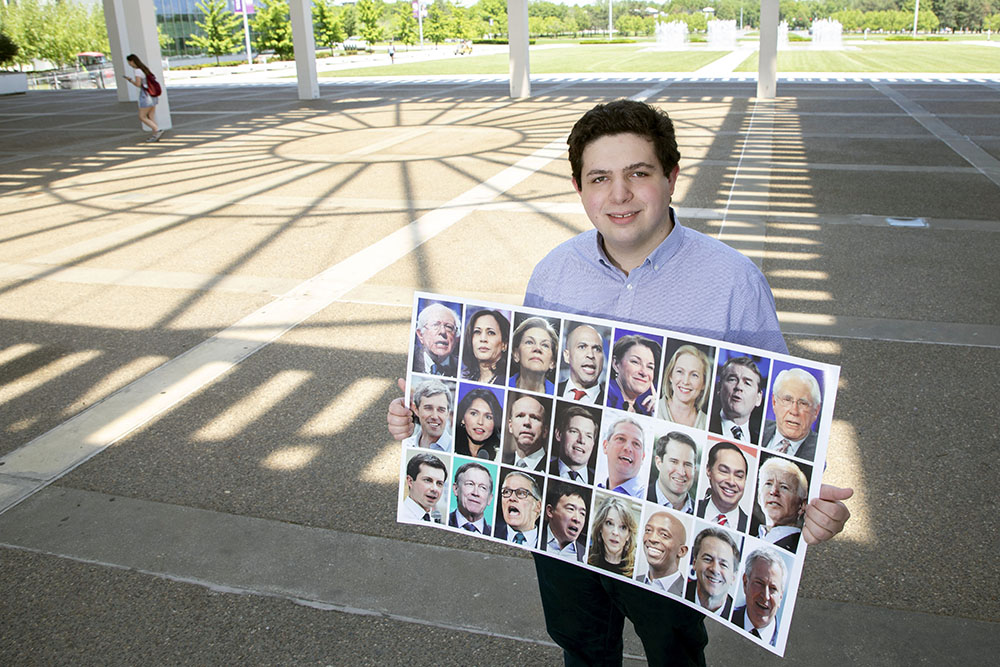 Public Administration grad student Austin Ostro holds up images of 24 Democrats vying to become the next president of the Unites States. 