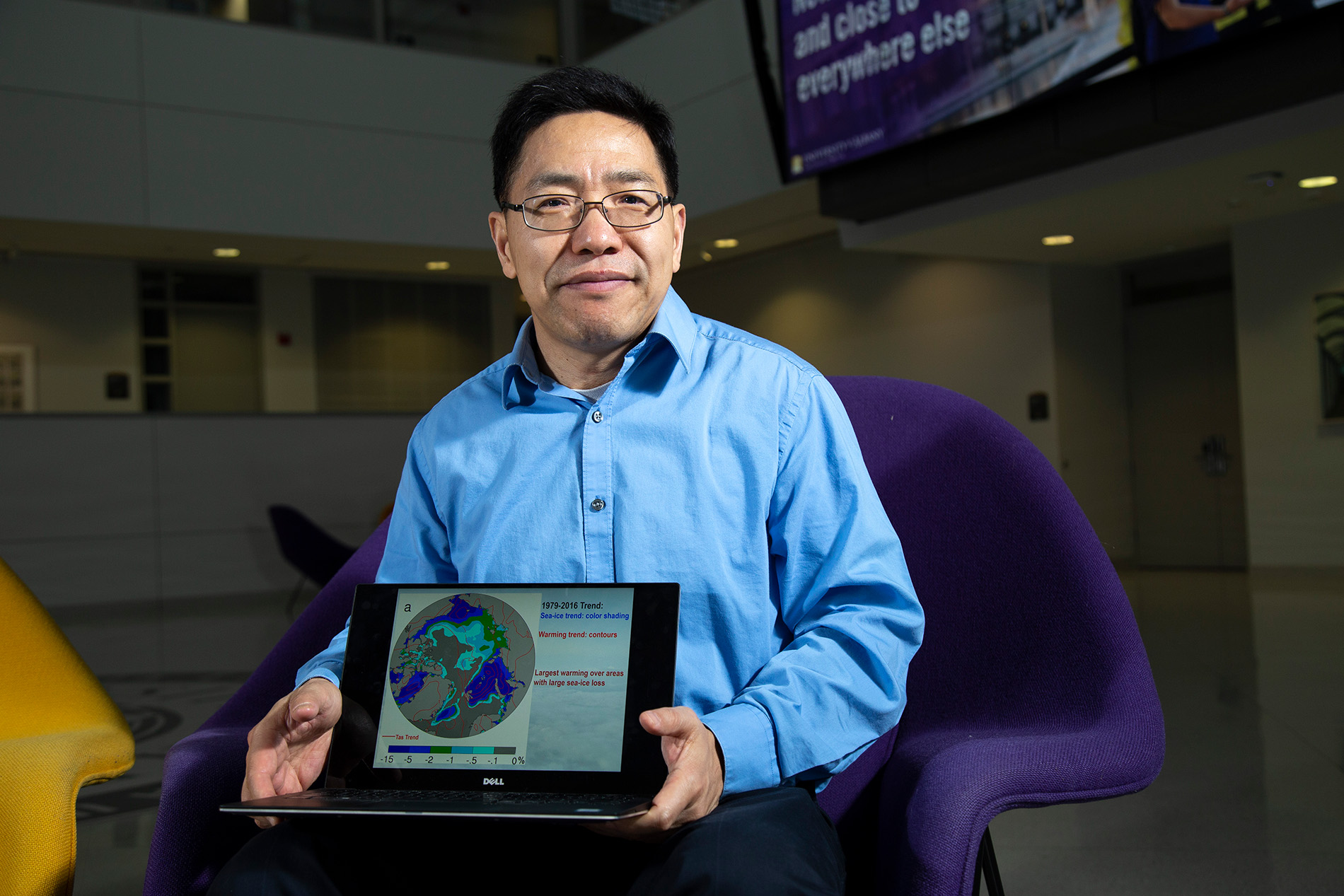 DAES professor Aiguo Dai shares a graphic of his research on a laptop inside University Hall.