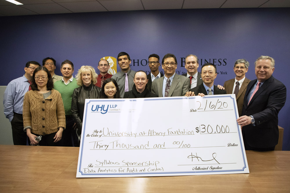 School of Business faculty and staff pose with a check and representatives from UHY