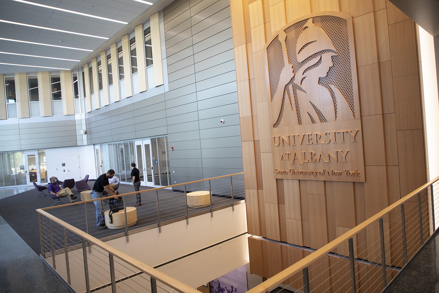 A view of ETEC's second floor lobby space with a large wood display of the Minerva logo.