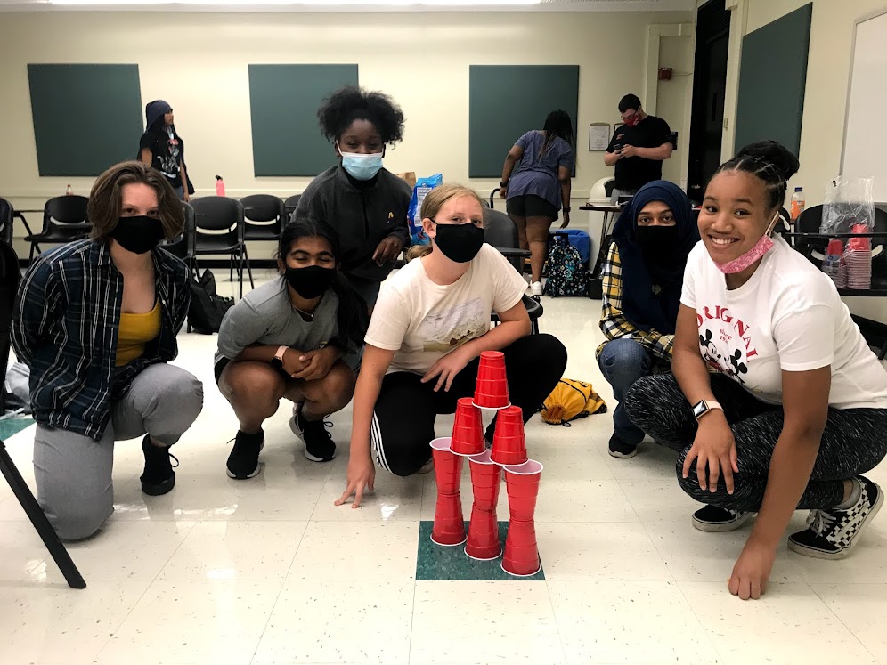 6 HS students gather around a pyramid of red drink cups in a classroom