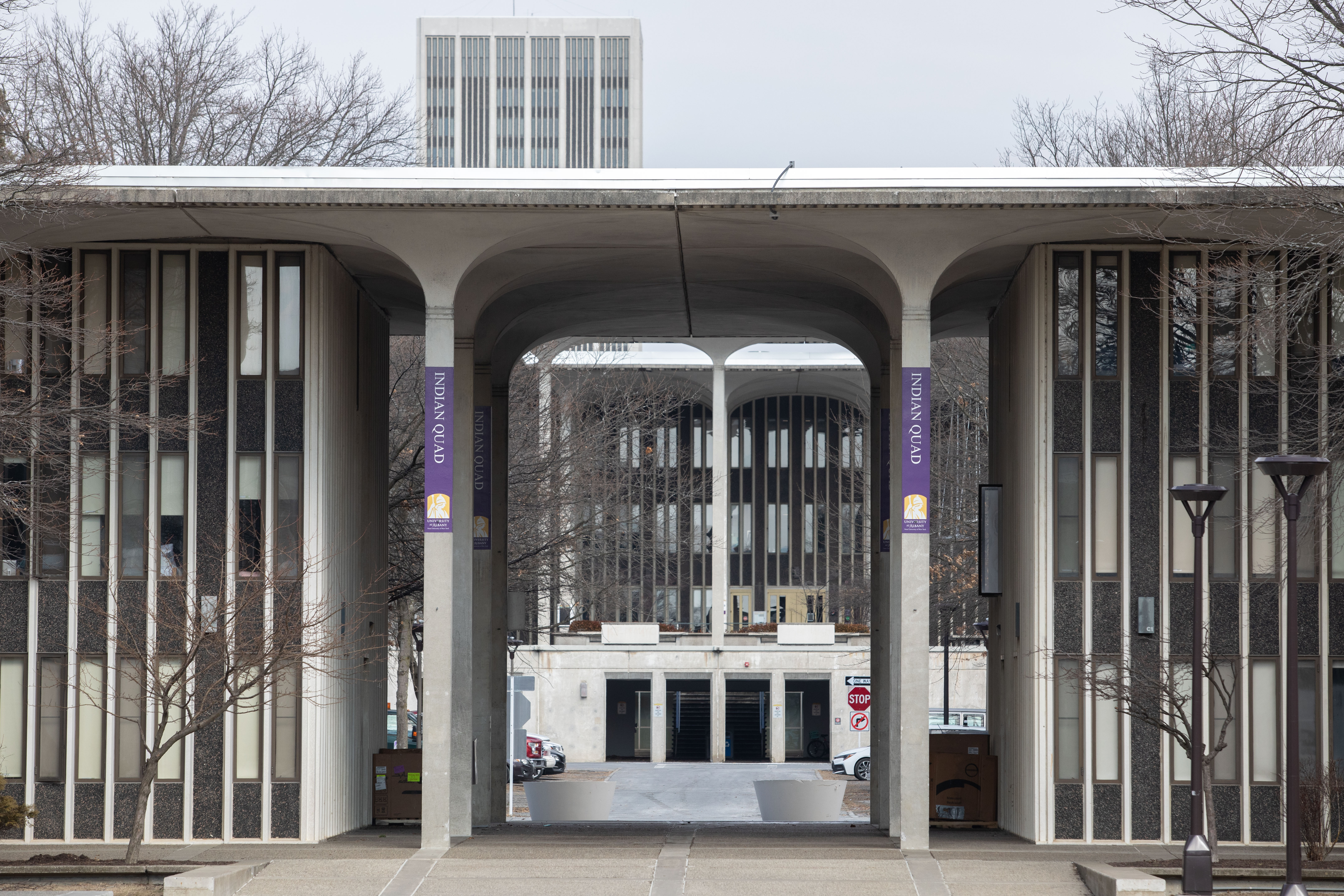 A large, concrete building with tall pillars and purple signs that say Indian Quad