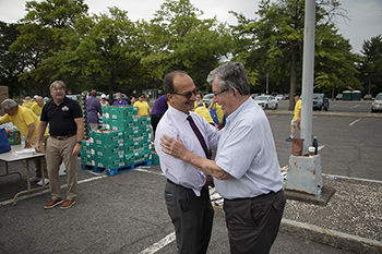 Sen. Breslin and UAlbany President Havidán Rodríguez embrace in a University parking lot with foot pallets in the background during a food giveaway on campus.