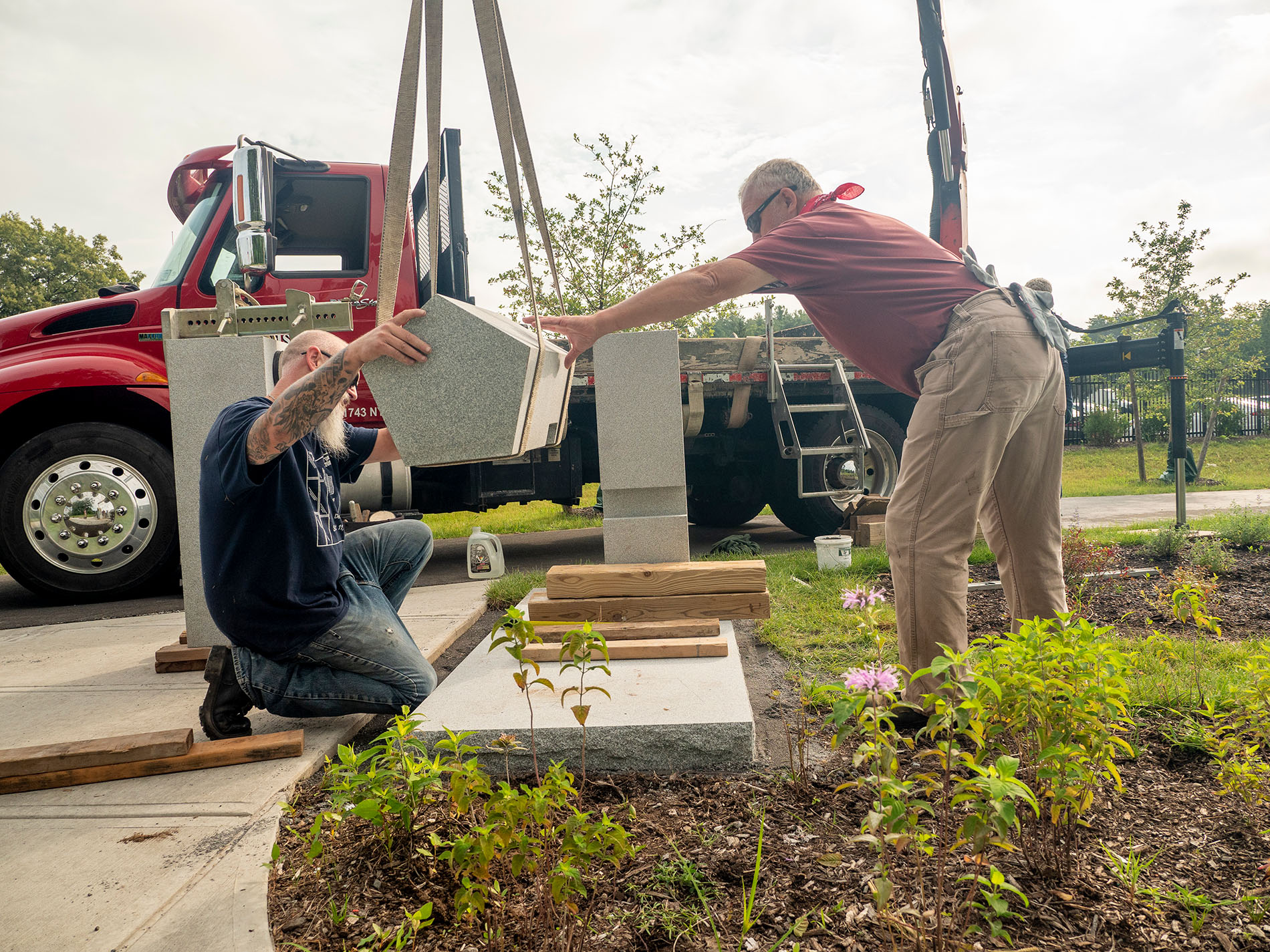 Contractors work together to install the 9/11 memorial bench on the new walking path to ETEC.