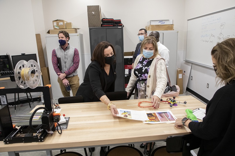 Representatives of the Griffiss Institute examine drone parts while standing around a table in the makerspace in UAlbany's ETEC building. 
