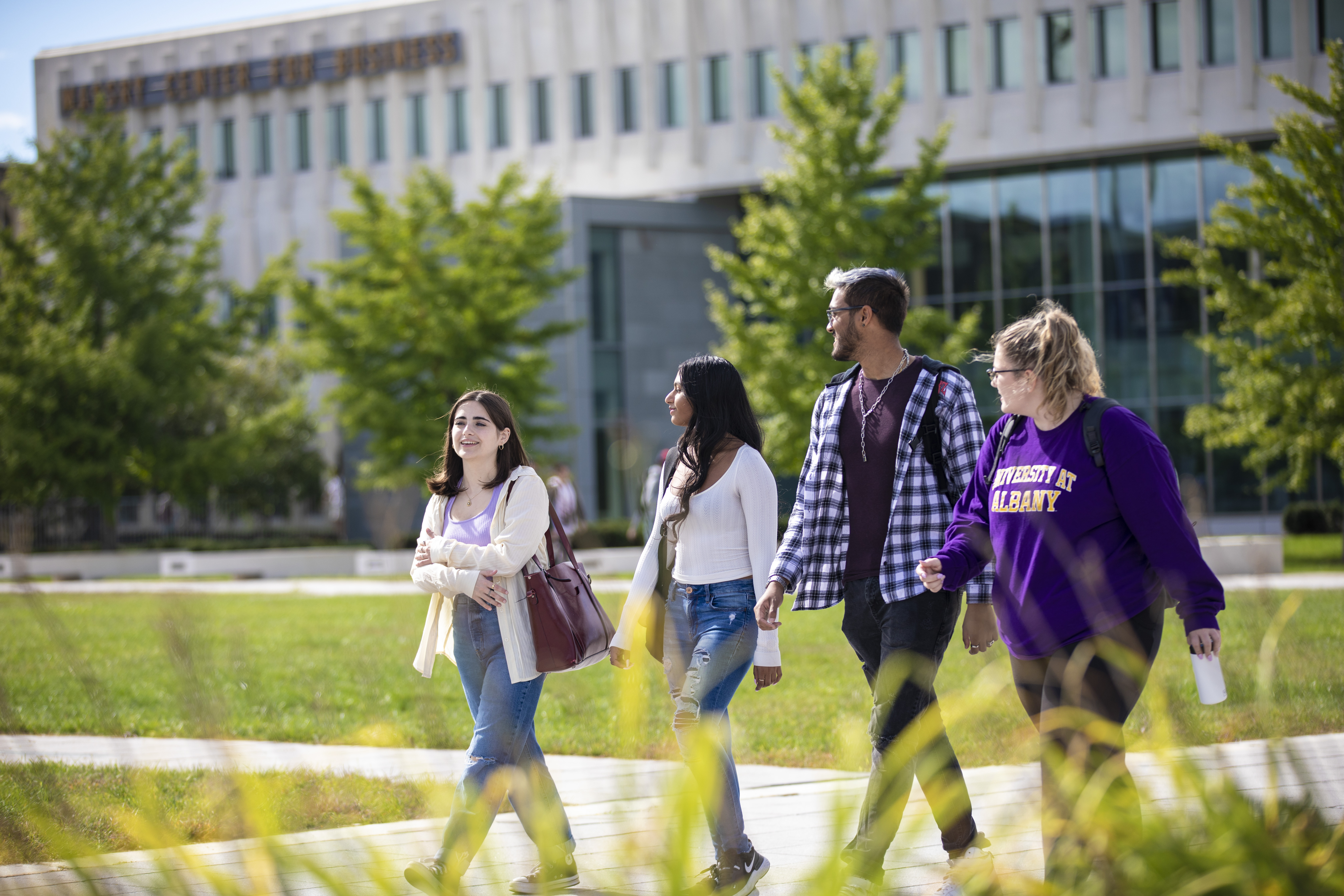 UAlbany students walk in a group around campus on a beautiful sunny day
