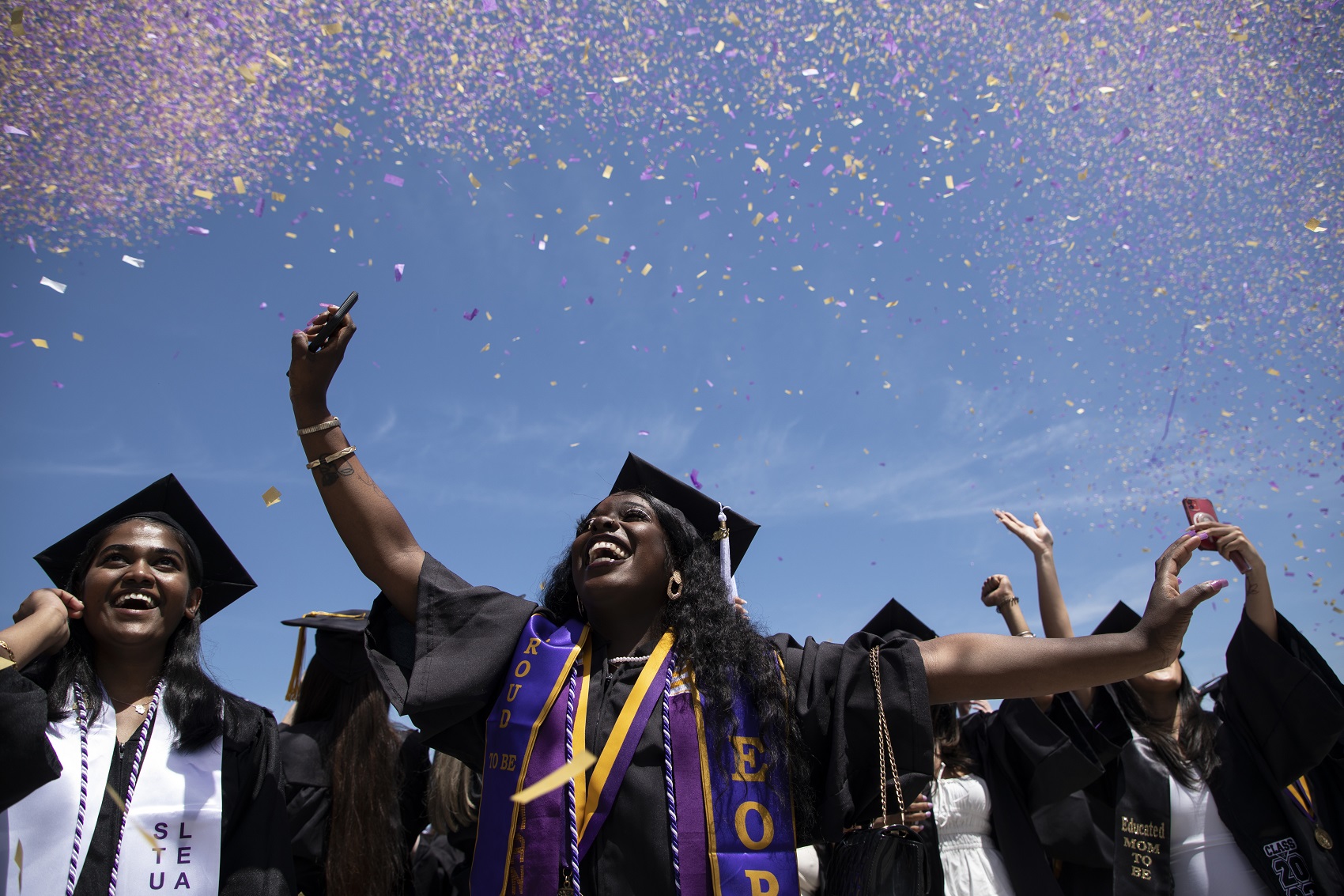 Students celebrate their official degree conferral at the Entry Plaza lawn with purple and gold confetti.