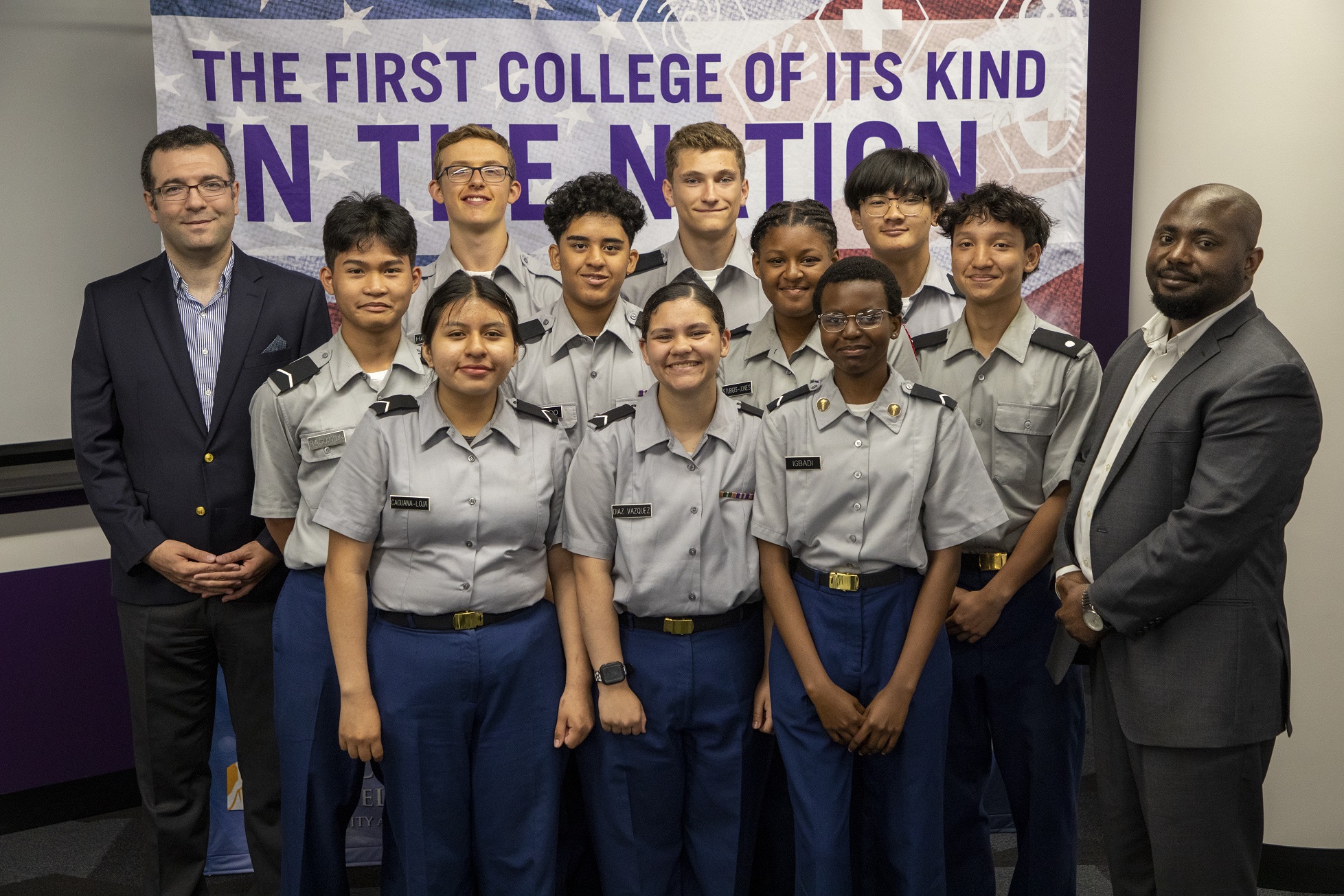 CEHC professors Unal Tatar and Benjamin Yankson stand with JROTC students in front of a CEHC banner.