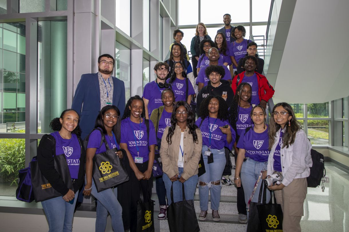  Students from the SPRINTER program, along with CEMHD Director Annis Golden and School of Public Health Professor Elizabeth Vasquez, pose for a group photo on a sunlit staircase in the RNA Institute.
