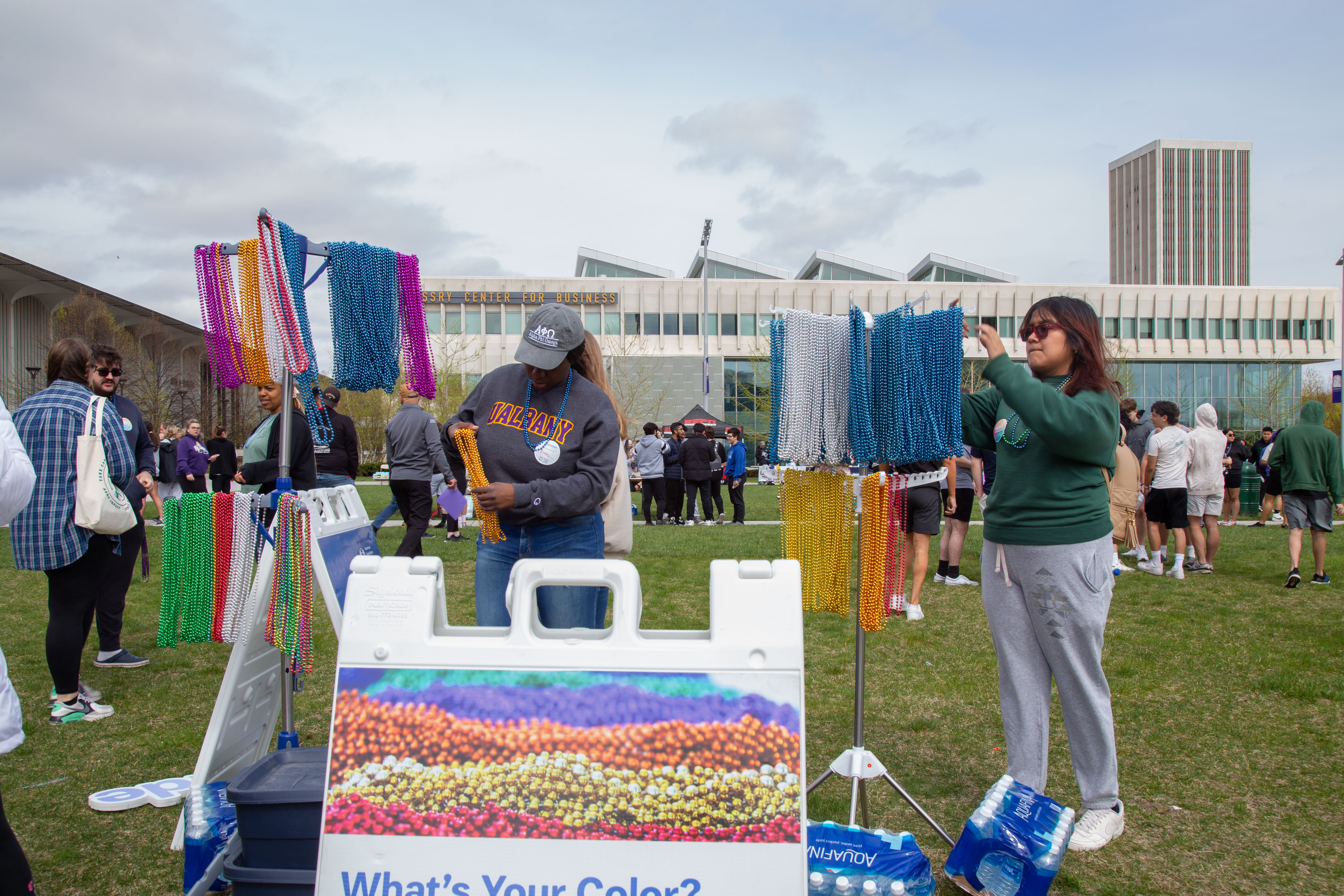 Students stand next two to racks of colorful beaded necklaces at the 2023 walk. The colors of the beads signify different connections someone might have to the issue of suicide. 