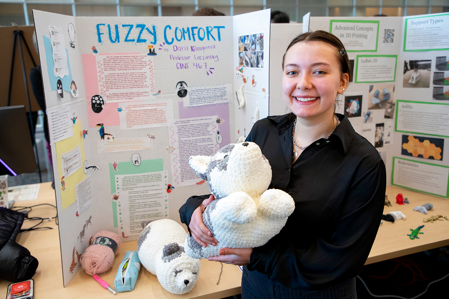 Student Daria Kolmogorova holds a stuffed animal in front of her poster project at CEHC's Fall 2023 Showcase.