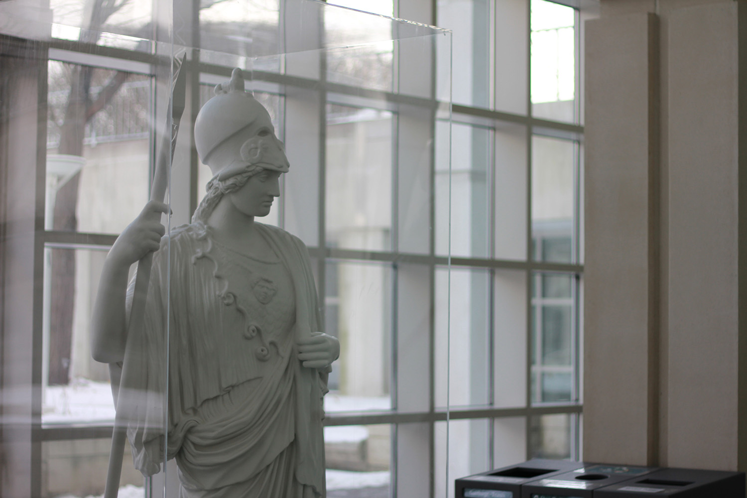 A white statue of Minerva in front of a wall of windows.