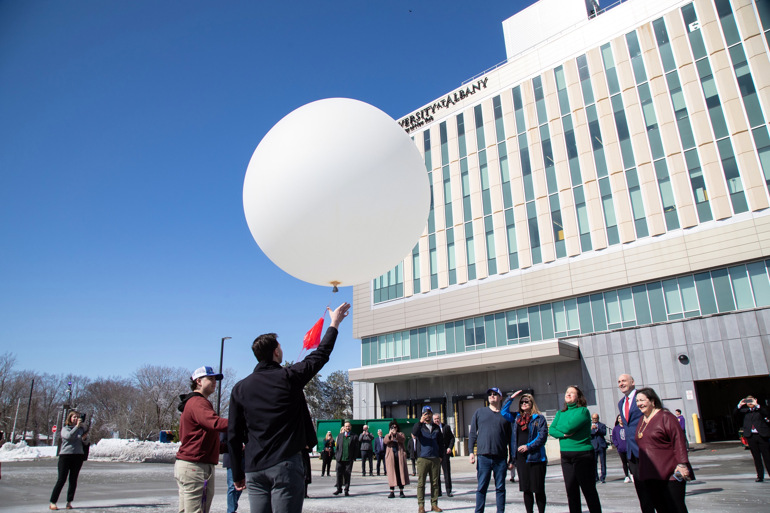 UAlbany students prepare to launch a weather balloon with state officials watching from the ETEC parking lot.