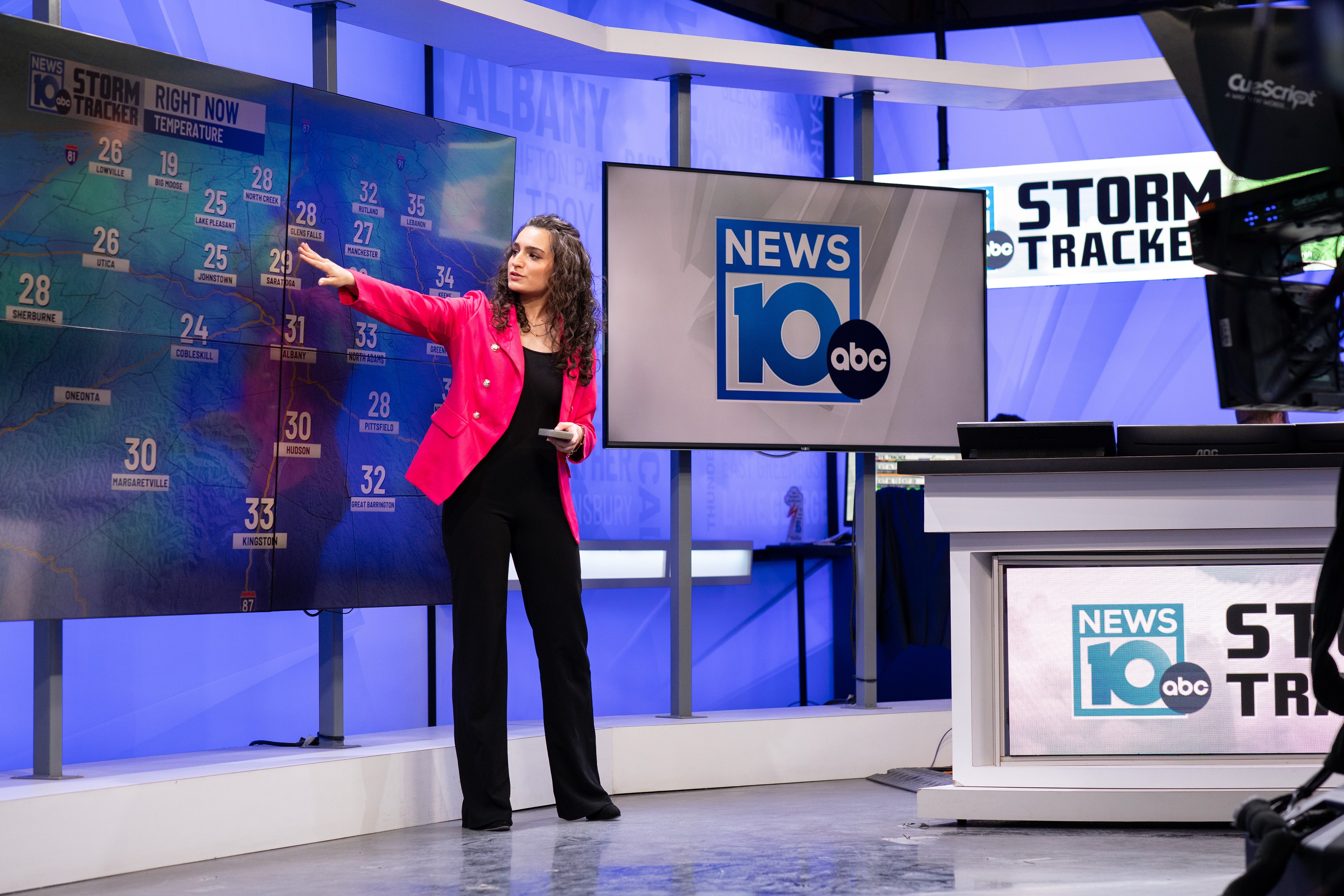 Jordan Due points at the weather forecast on a large LED screen inside the NEWS10 ABC studio.