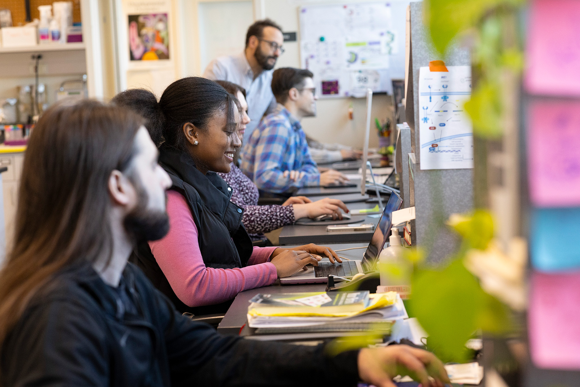 Student researchers sit in a row, working at a bank of computers. 