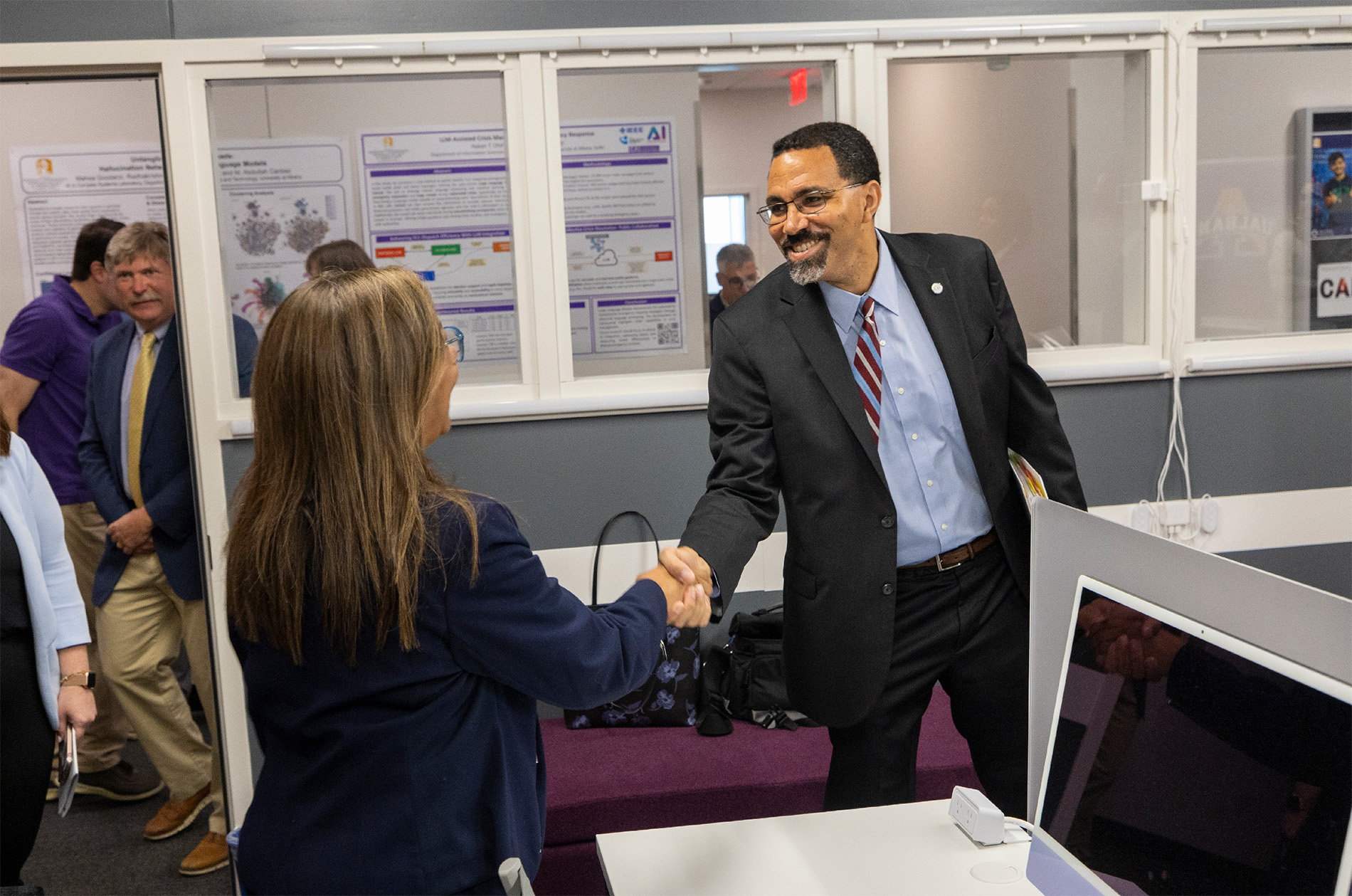 Chancellor King shakes hands with Mayra Santiago at the AI in Complex Systems Laboratory.