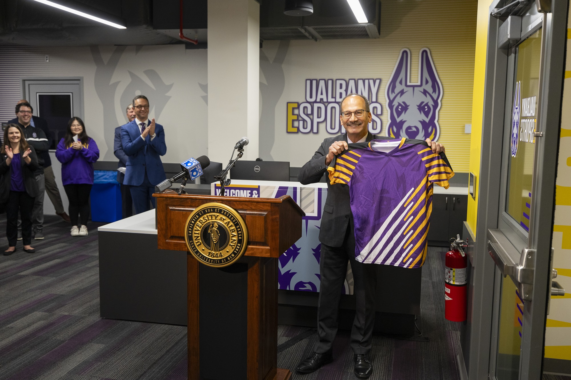 President Rodriguez holds up an honorary UAlbany Esports jersey at the unveiling of the new arena. 