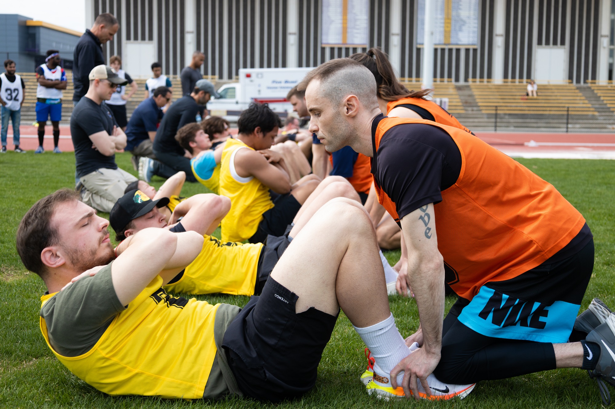 UAlbany students wear orange and yellow jerseys while completing sit ups during the FBI physical fitness test. 