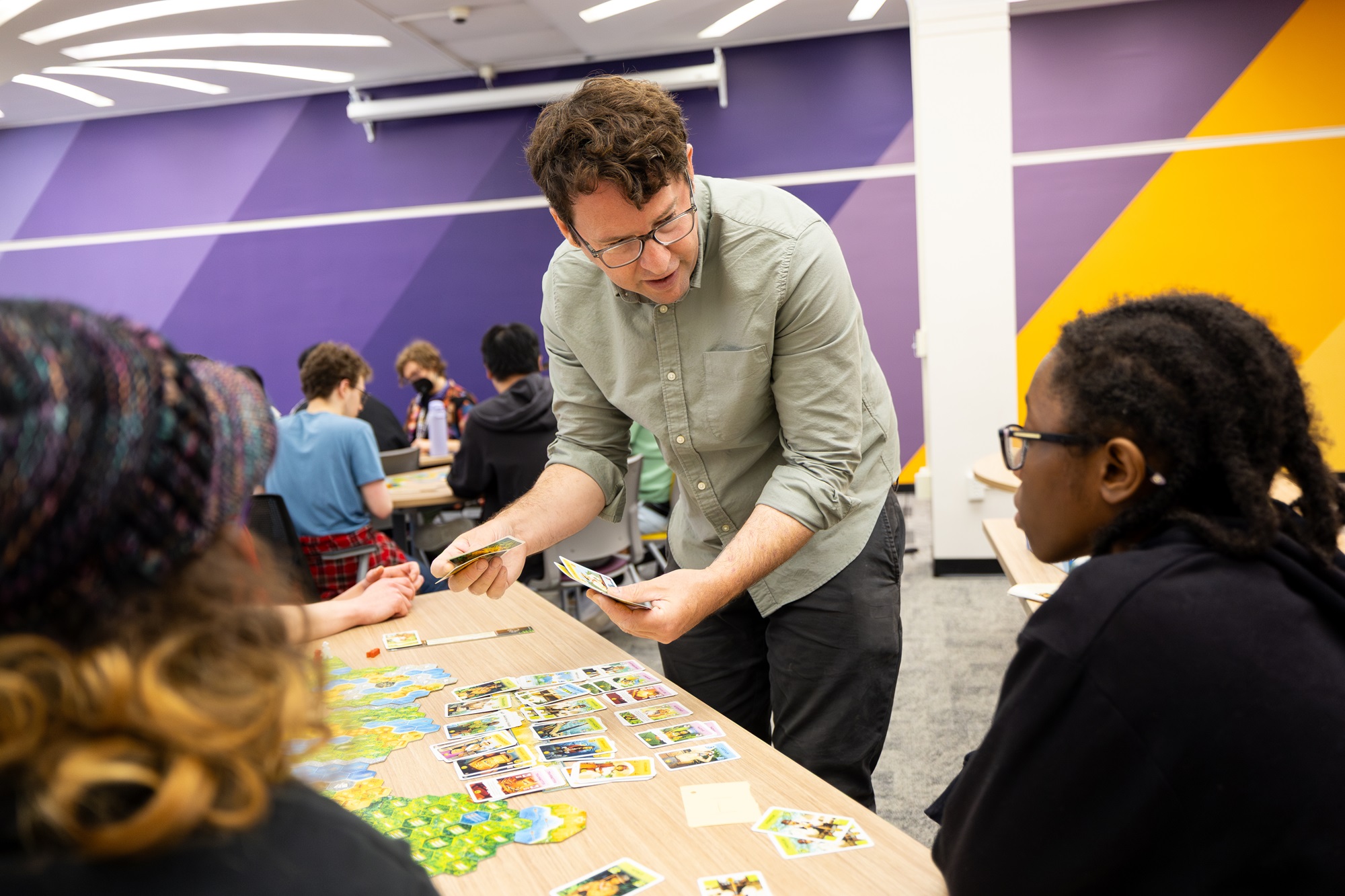Jason Corace holds playing cards while interacting with students in his Game 100 course.
