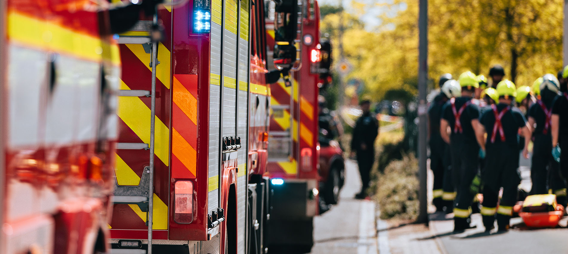 A group of first responders gather next to a line of fire engines to plan an emergency response.