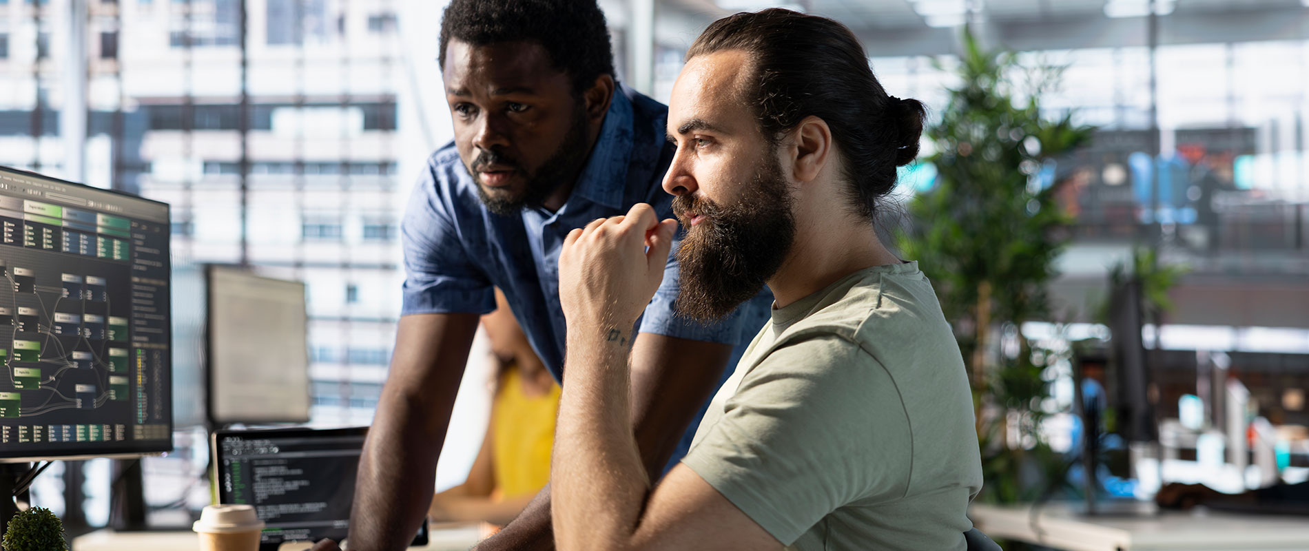 Two ethical hackers review code on a monitor.