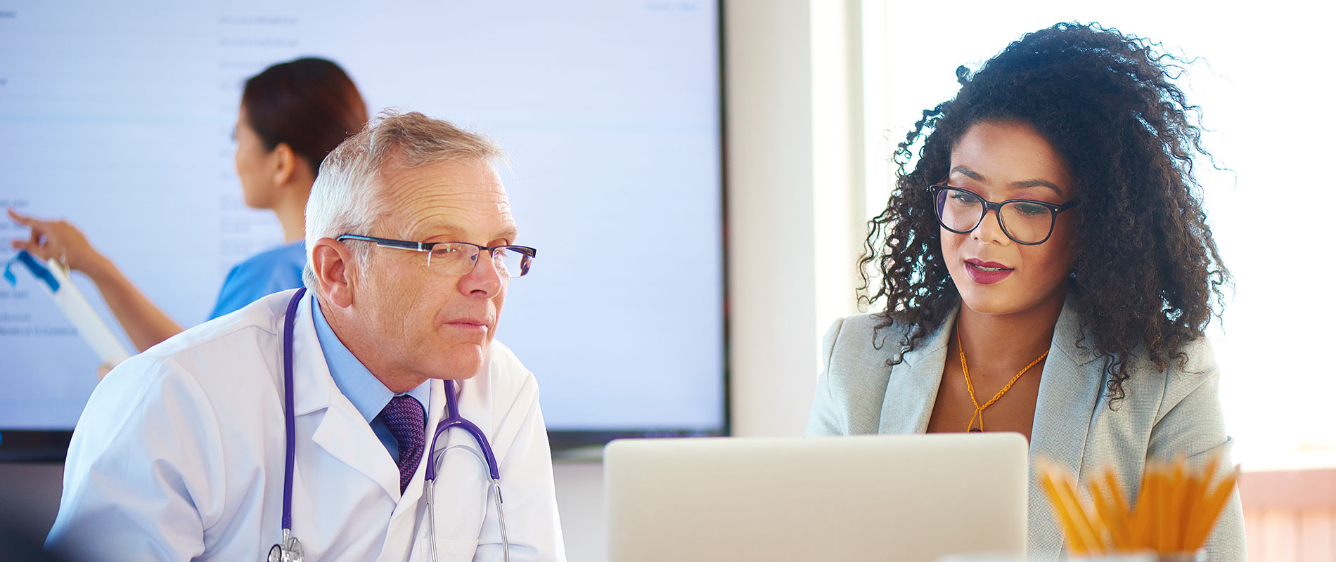 A clinical informatics specialist discusses an EHR-related issue with a doctor.