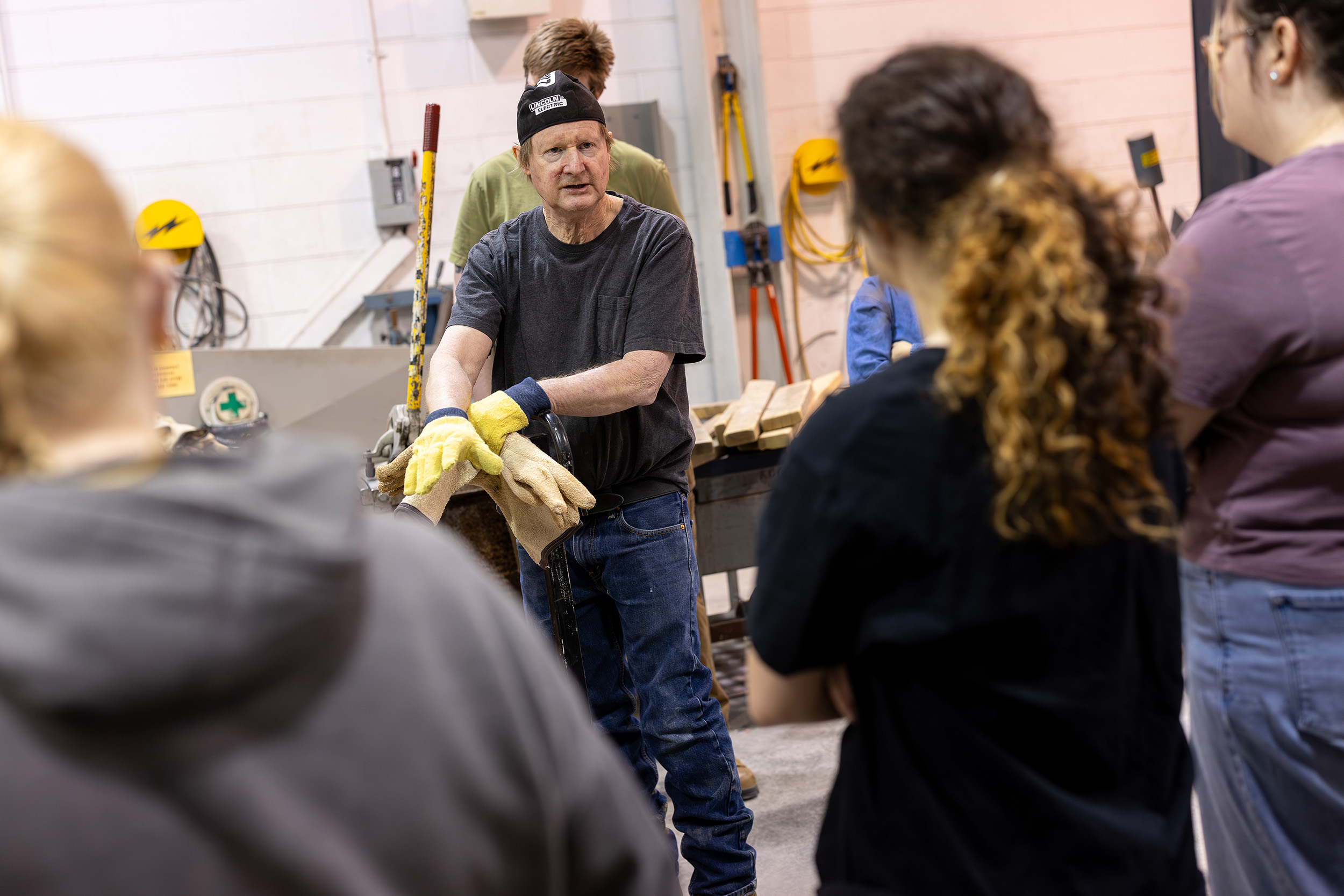 Roger Bisbing, instructional support technician in sculpture speaks with students inside the Boor Sculpture studio during a metal pour. ( Photo by Patrick Dodson)