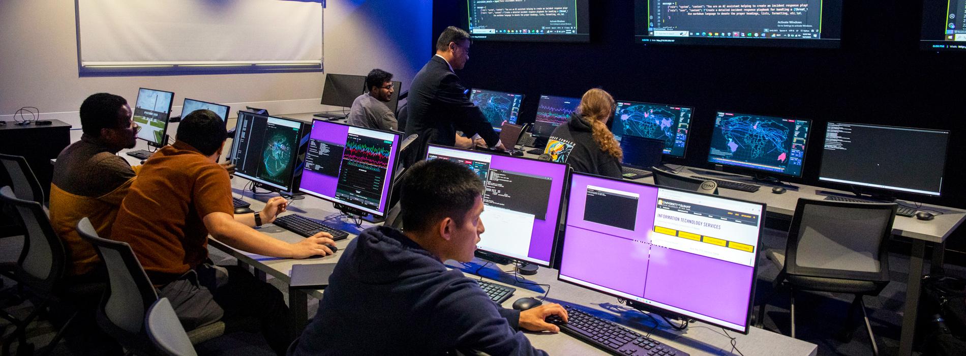 A group of students working in front of multiple monitors in UAlbany's cybersecurity lab.