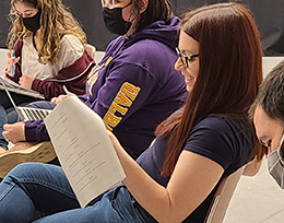 A female student actress laughs at something in the script she holds