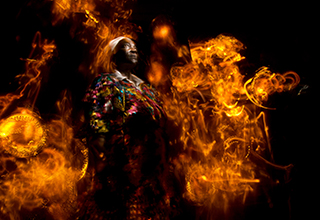 A photo of a man in African dashiki amidst burning flames of gold 