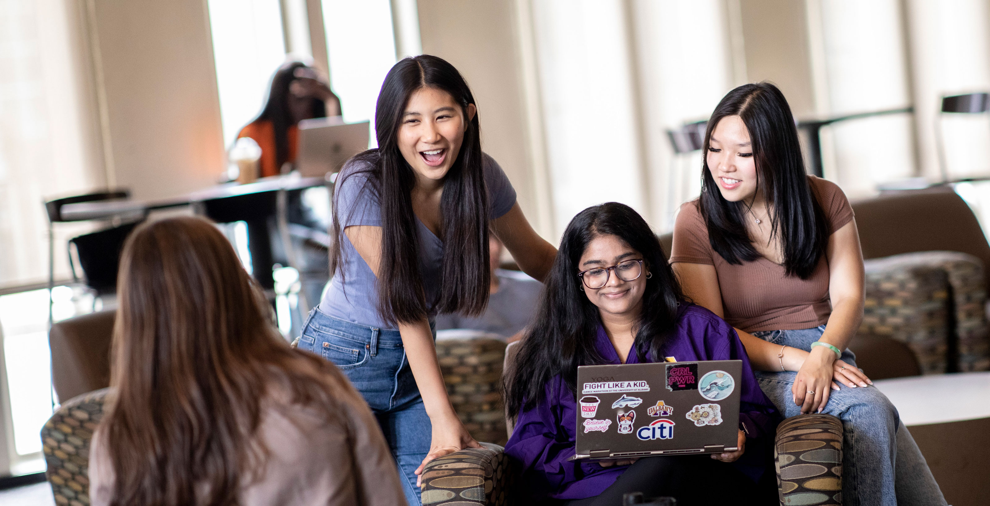 Four students smile and laugh as they hang out in a group study area.