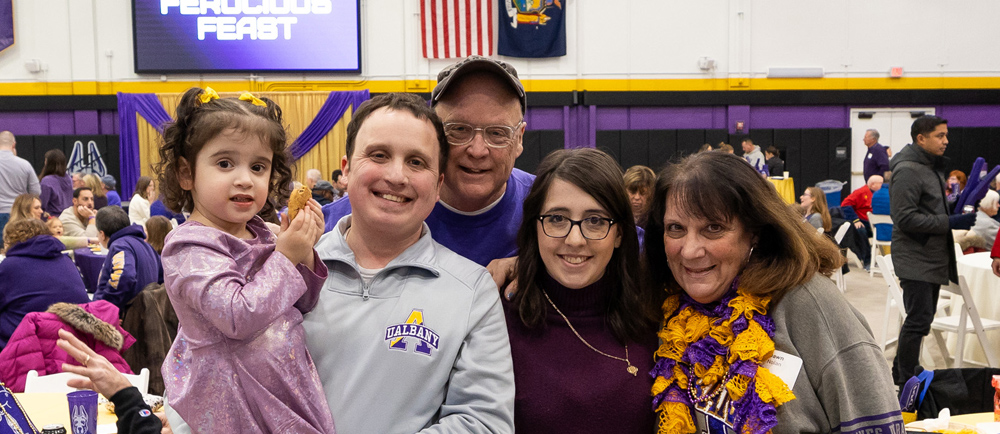 A family gathers for a photo inside the UAlbany PE gym.
