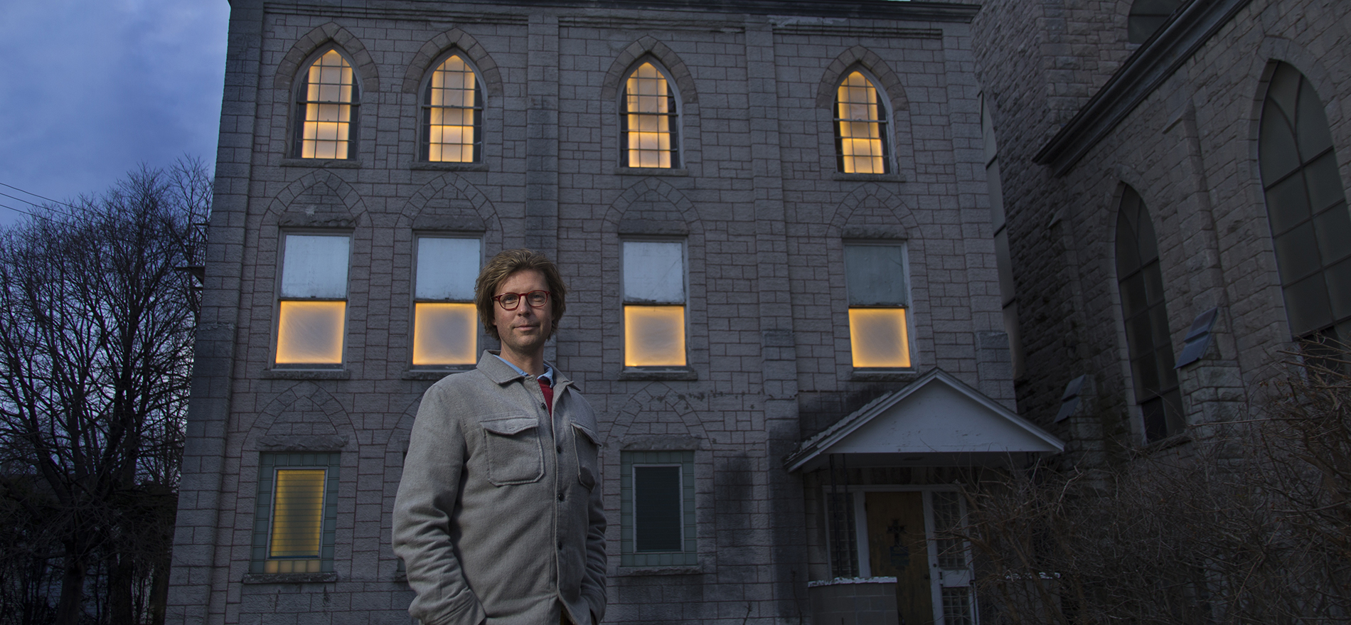 Professor Adam Frelin stands in front of one of the buildings included in his public art project entitled 'Breathing Lights'. The multi-city installation transforms abandoned structures into glowing places of warmth. Photographer: Paul Miller
