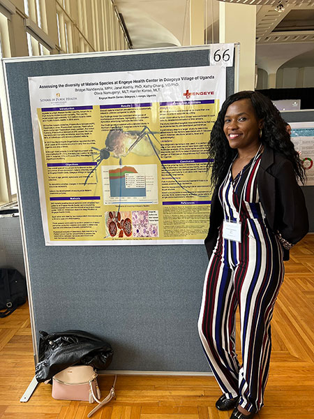 Bridget Nandawula standing with a research poster presentation