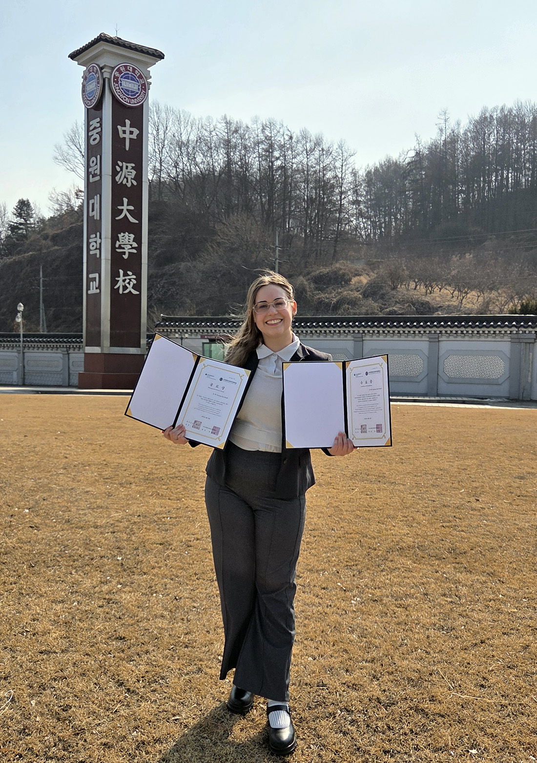 Kate Bucek stands in Korea with her awards from Fulbright for learning the Jeju dialect of Korean.